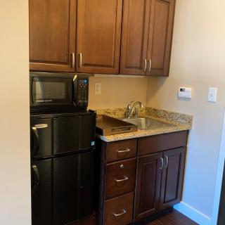 A compact kitchen area featuring a microwave, refrigerator, and wooden cabinets.