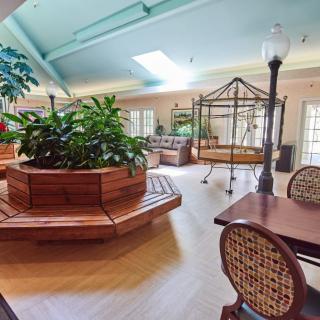 A bright indoor seating area with wooden benches, plants, and tables under a skylight.