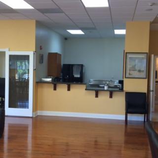 A spacious waiting area with wooden flooring and a reception counter.