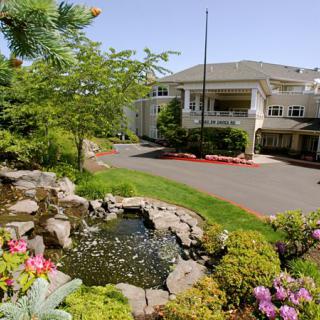 A serene garden view with a pond in front of a large building.