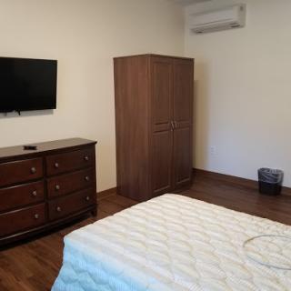 A neatly arranged bedroom featuring essential furniture, including a TV and wardrobe.