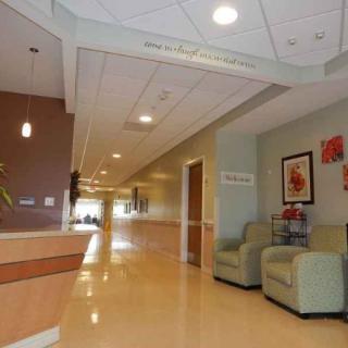 A hospital lobby with a reception desk, seating area, and hallway.