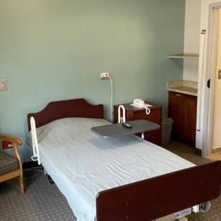 A hospital room with a single bed, tray table, and medical equipment.
