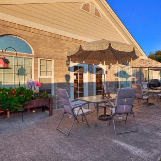 A cozy outdoor patio area with tables, chairs, and umbrellas adjacent to a building.