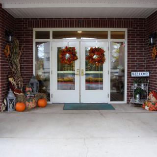 An entryway decorated with autumn-themed items, including pumpkins, wreaths, and corn stalks.