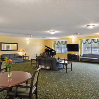 A spacious living room with a piano, sofas, and a television.