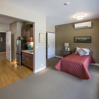 A cozy studio apartment with an integrated kitchenette and a comfortable bed.