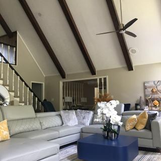 A modern living room with a vaulted ceiling, featuring a large sectional sofa and a central coffee table adorned with flowers.
