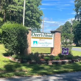 Entrance sign for Deer's Head community surrounded by greenery.
