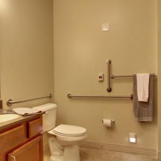 A modern, accessible bathroom with a toilet, sink, and grab bars for safety.