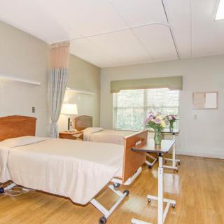 An empty hospital room with two beds and a window, providing a clean and calming environment for patient care.