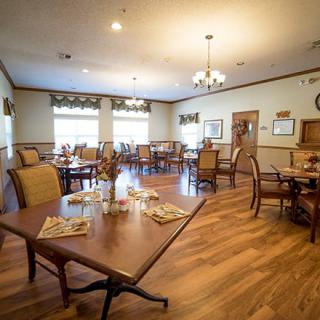 A cozy dining room with elegantly arranged tables and chairs on a hardwood floor.