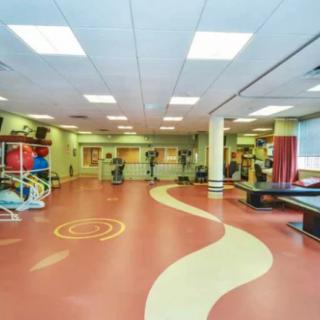 A spacious fitness center with various exercise equipment and a unique floor design.