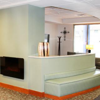 A modern lobby featuring green walls, a unique seating area, and a cozy fireplace.