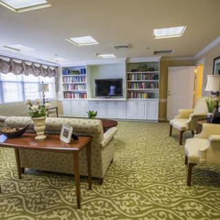 A cozy living room with a sofa, chairs, bookshelves, and a television.