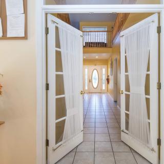 A view of a bright residential hallway with double doors and tiled flooring.