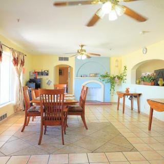 A spacious and inviting dining area featuring a wooden table set for six, complemented by warm yellow walls and natural light.