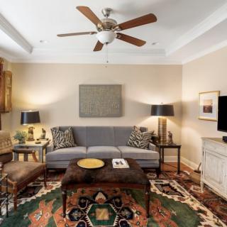 A cozy living room with modern decor, featuring a gray sofa, patterned rug, and a ceiling fan.