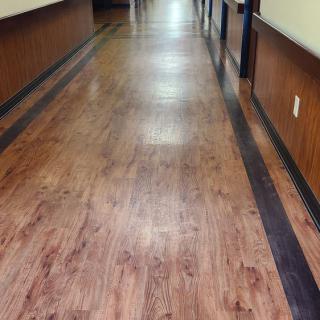 A long hallway with wooden flooring and lined walls.