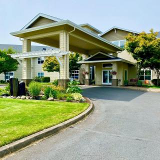 A well-maintained building entrance with landscaped surroundings and a driveway.