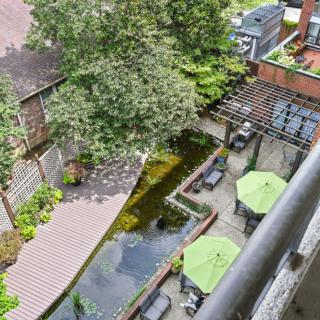 A serene garden view with a pond and outdoor seating area featuring green umbrellas.