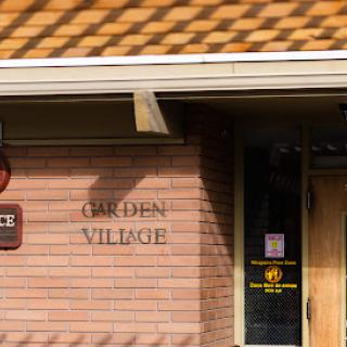 The entrance of Garden Village, featuring a prominent sign on a brick facade.