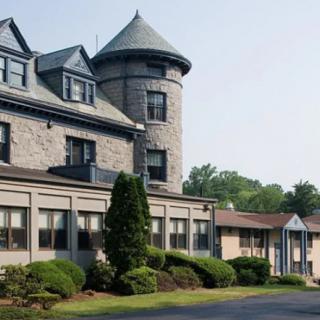 A historic stone building with a round tower and manicured landscaping.