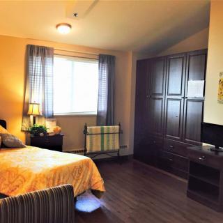 A cozy bedroom with a bed, a wardrobe, and a window allowing natural light in.