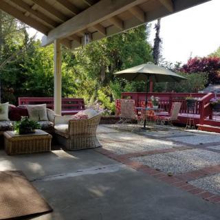 A cozy outdoor patio with comfortable seating and lush garden surroundings.