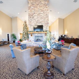 A spacious living room with a stone fireplace, comfortable seating, and holiday decorations.