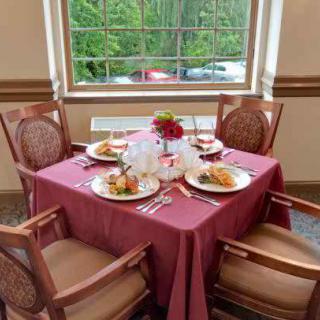 A beautifully set dining table for four, complete with plated meals and decorative centerpieces by a window.