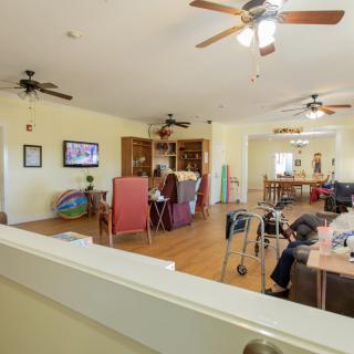 A spacious living room with furniture, ceiling fans, and people engaging in activities.