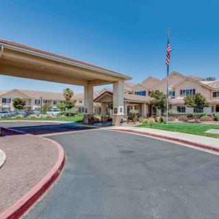 A large building with a covered entrance and well-maintained landscaping on a sunny day.