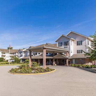 A modern senior living residence with a driveway and landscaped entrance.