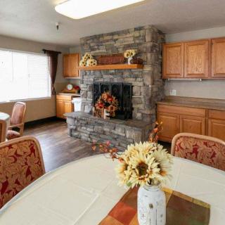 A cozy dining area featuring a stone fireplace and wooden cabinets, bathed in natural light.