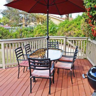 An outdoor patio deck with a table, chairs, and an umbrella set up for relaxation.