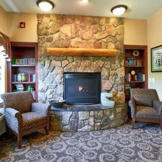 A cozy living room with a stone fireplace, armchairs, and bookshelves.