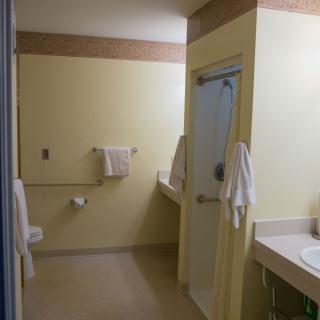 A clean, accessible bathroom with towels, a sink, and a shower.