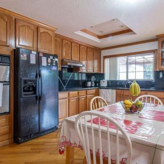A spacious kitchen with wooden cabinets, black appliances, and a dining table set near a window.