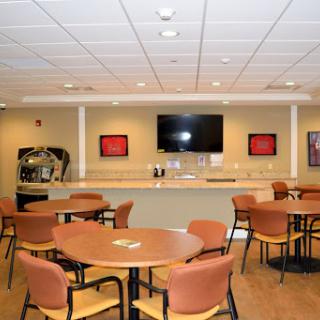 A well-furnished common area featuring tables, chairs, and a television.
