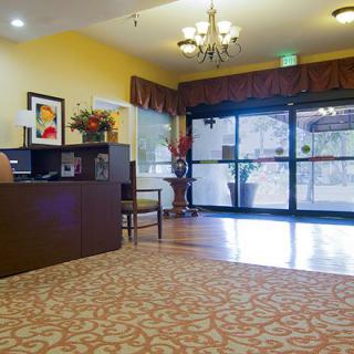 A cozy lobby area with a reception desk, elegant chandelier, and large glass entrance doors.