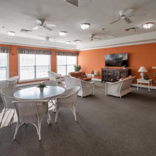 A cozy living room with rattan furniture and an orange accent wall.
