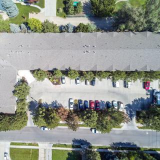 Aerial view of an apartment complex with a parking lot surrounded by trees.