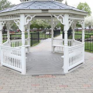 A white wooden gazebo in a park setting.
