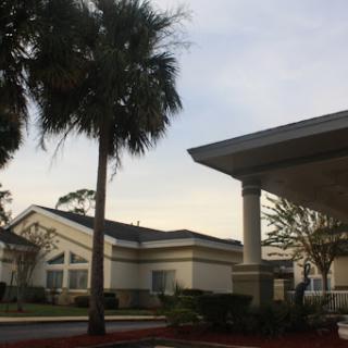 A view of a residential area featuring modern architecture and palm trees under a cloudy sky.