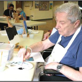 A senior person engaged in painting during an art class.