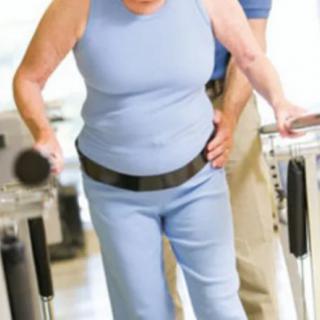 An elderly person receiving support during a physical therapy session.