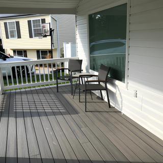 A cozy porch with chairs and a table in a suburban residential setting.