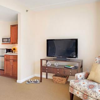 A cozy living room with a television and a glimpse into the kitchen area.