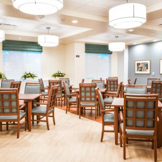 A spacious dining area with neatly arranged tables and chairs, featuring elegant lighting fixtures.